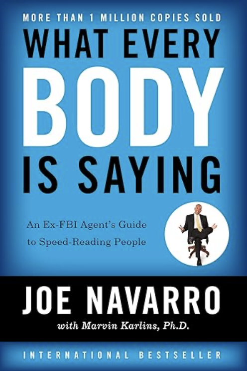 Book cover titled 'What Every Body is Saying' by Joe Navarro, with Marvin Karlins, Ph.D., featuring a small image of a man sitting on a chair with arms and legs spread.