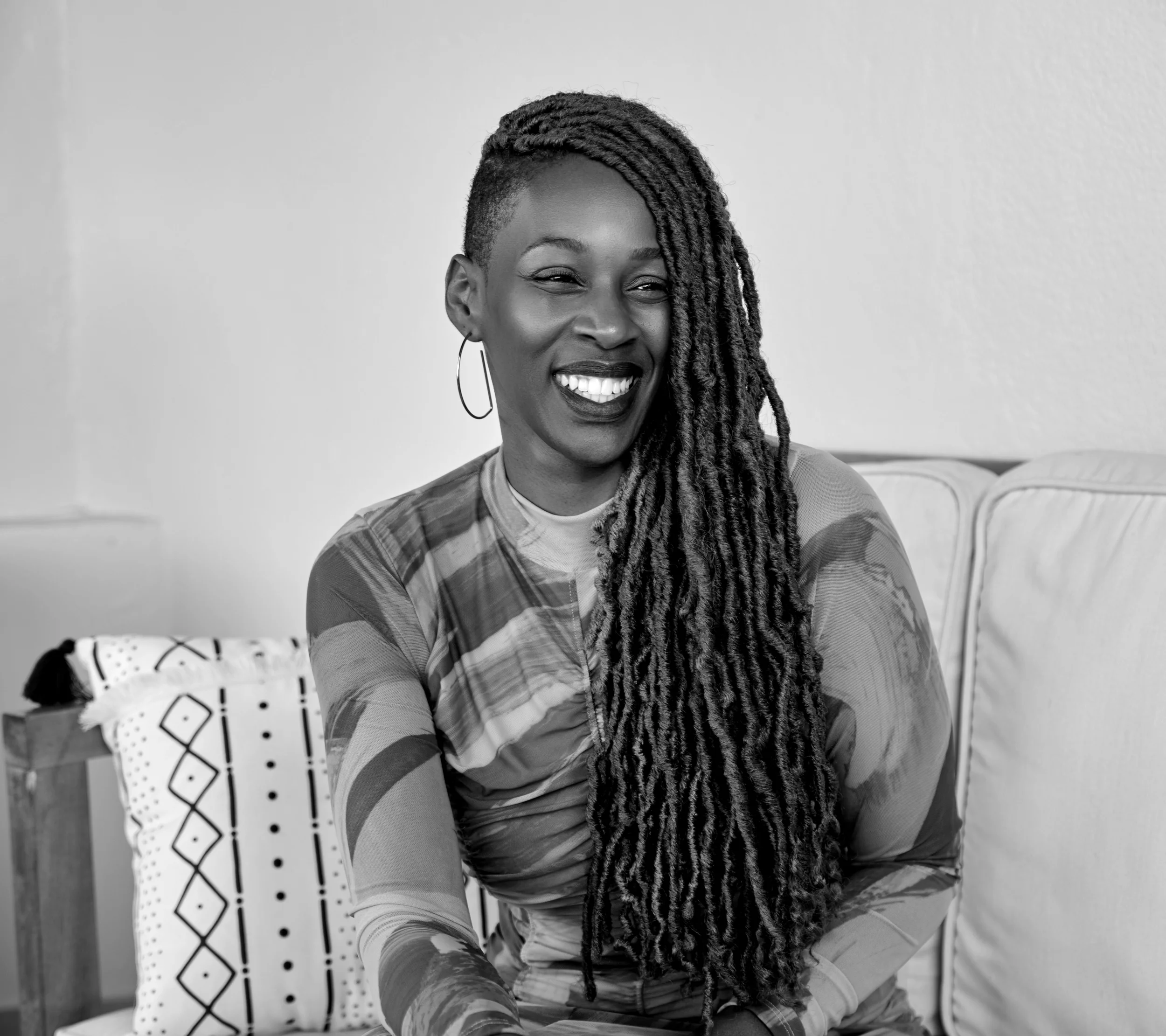 Black and white photo of Dr. Yanique Redwood wearing a long-sleeved patterned dress with long dreadlocks
