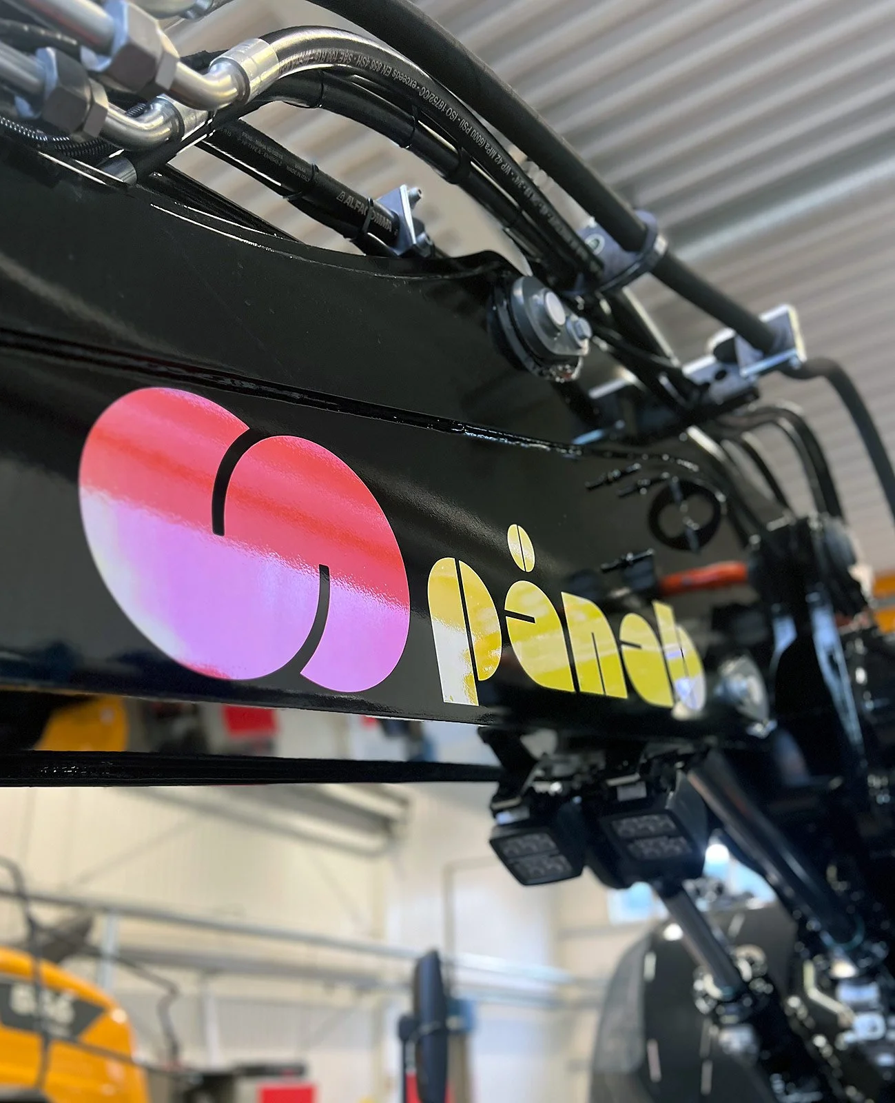 Detalj av maskindekor med logotyp för Pinab på entreprenadmaskin i verkstadsmiljö i Luleå, Norrbotten