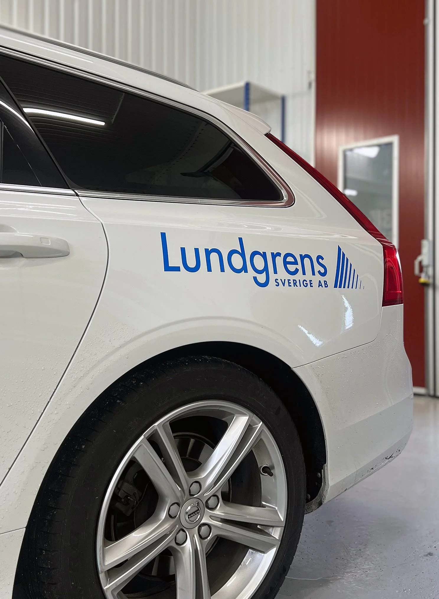 Bildekor med logotyp för Lundgrens Sverige AB på vit Volvo i verkstadsmiljö i Luleå, Norrbotten