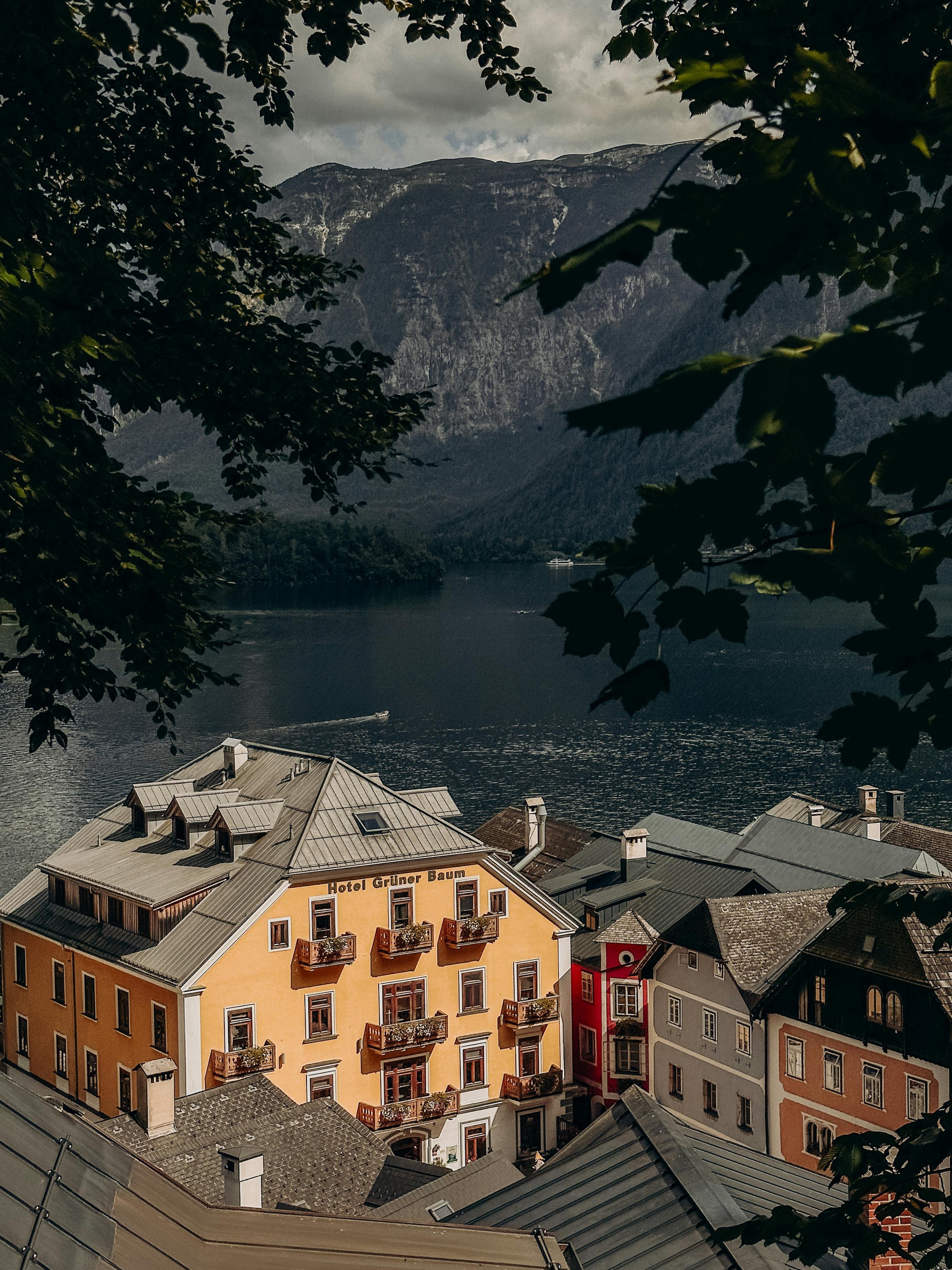 A view of a lakeside town with colorful buildings, overlooking a lake surrounded by mountains and trees in the foreground.