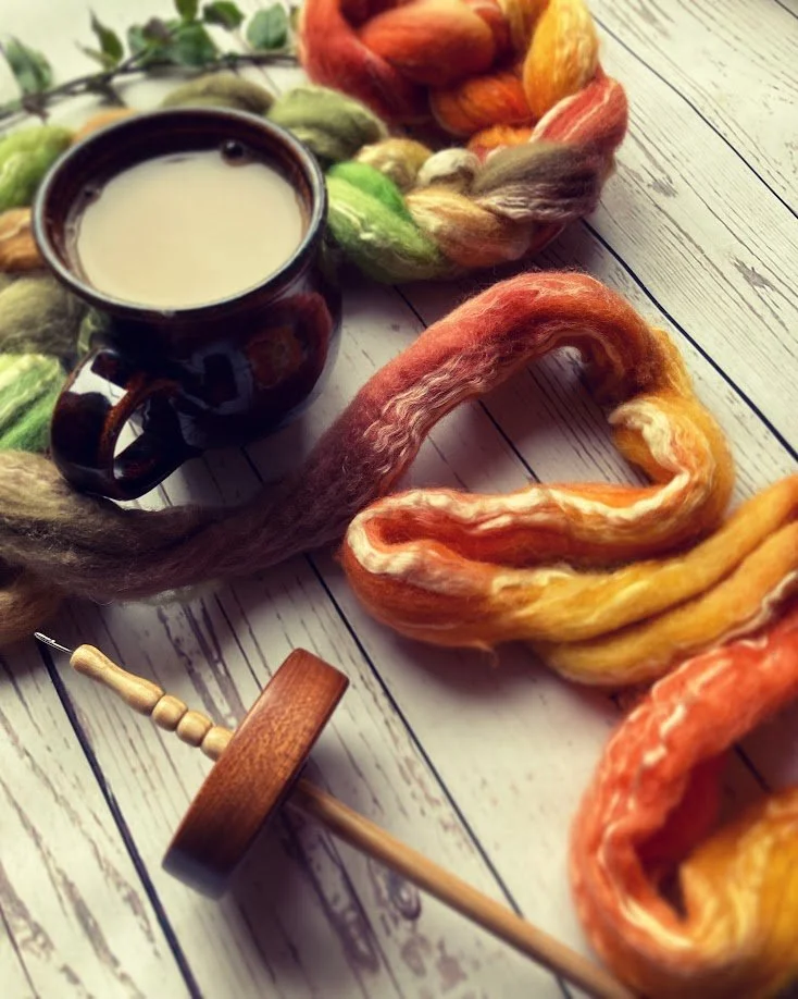 Colorful wool yarn and a cup of milk on a white wooden surface.