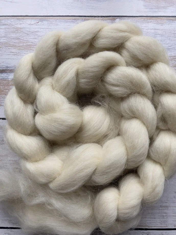 Cream-colored, thick braided wool or fiber on a wooden background.