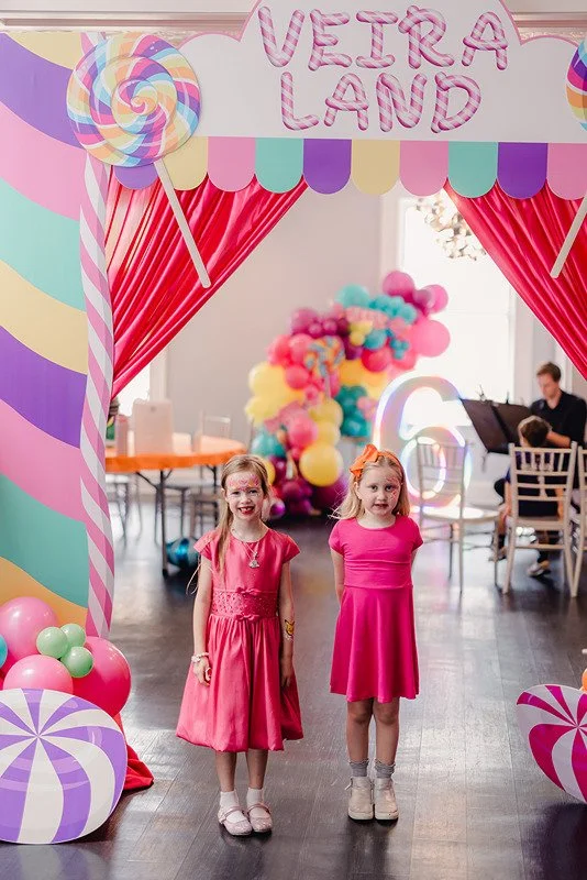 Birthday girl and friend posing at the immersive Candyland-themed event entrance at Sweet Pete’s Candy Shop in Jacksonville, Florida