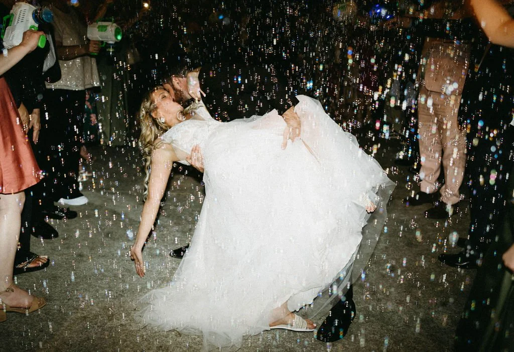 Bride and groom share a dipped kiss during their bubble exit at an artfully designed Atlanta wedding by Port Town Collective