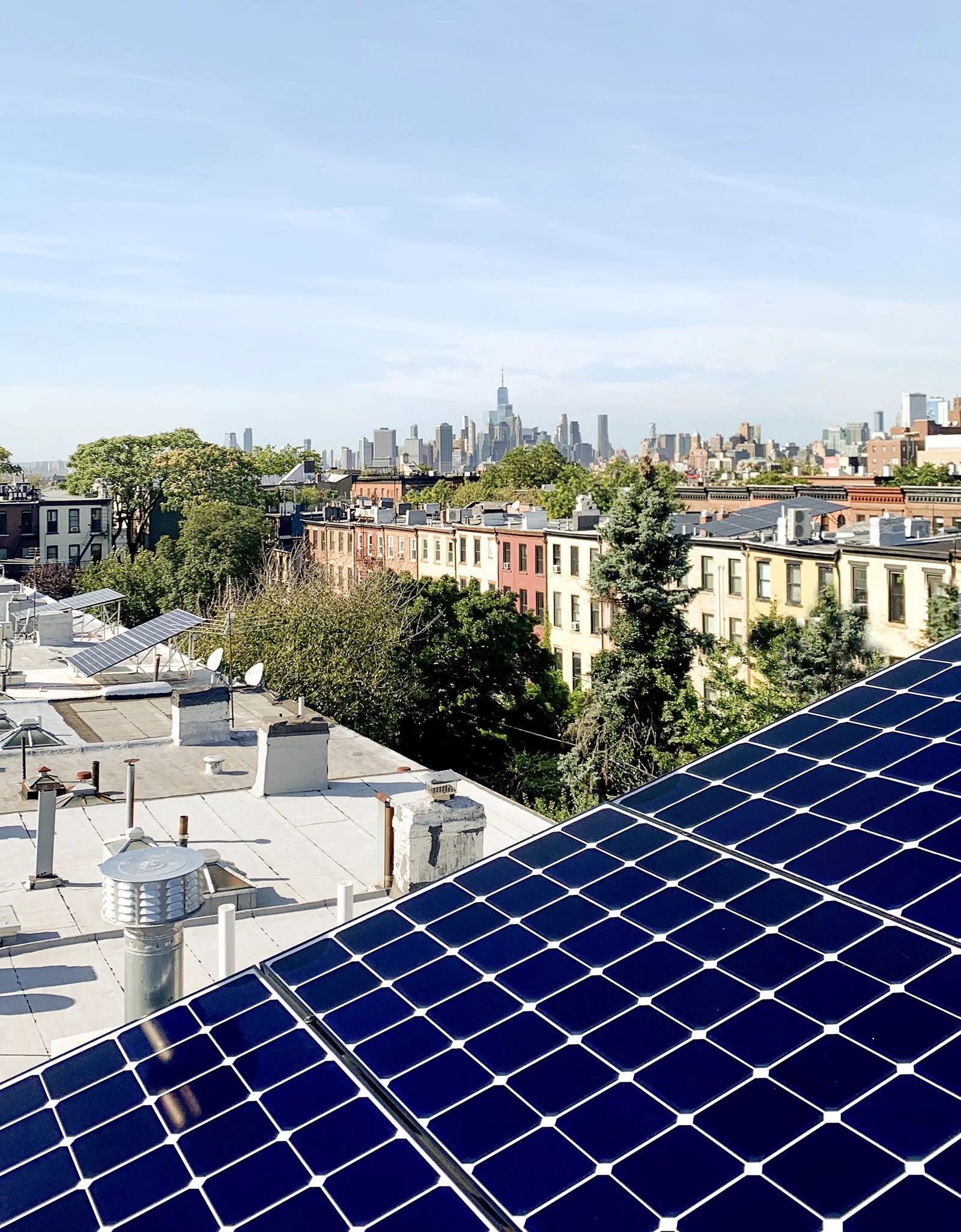 Solar panels on rooftop with city skyline and trees in background