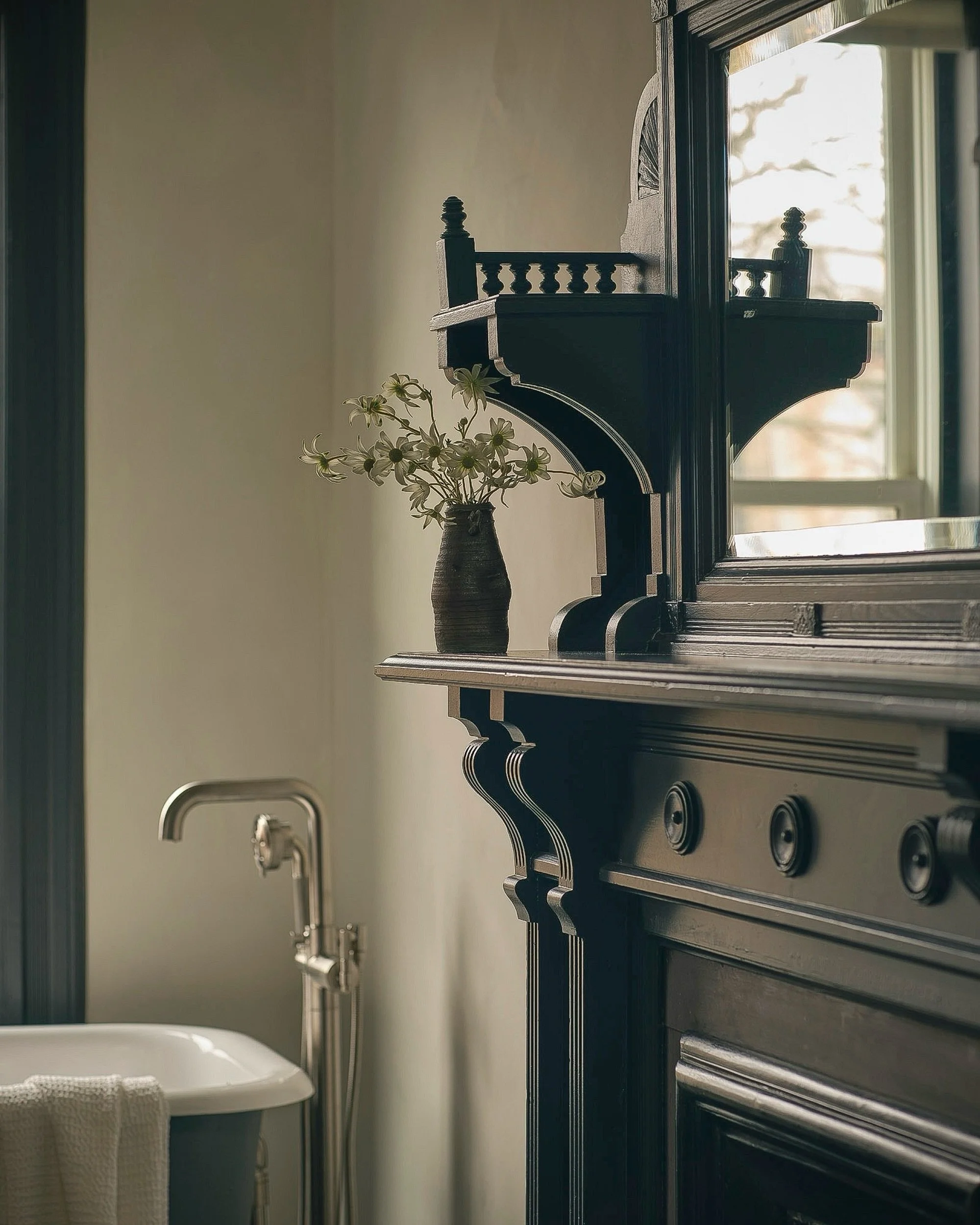 In the primary bath at Oculus House, a restrained black-and-white palette brings old and new into sharper focus. The clawfoot tub was found elsewhere in the house - repurposed, refinished, and given a new place - while the original late-19th-century 