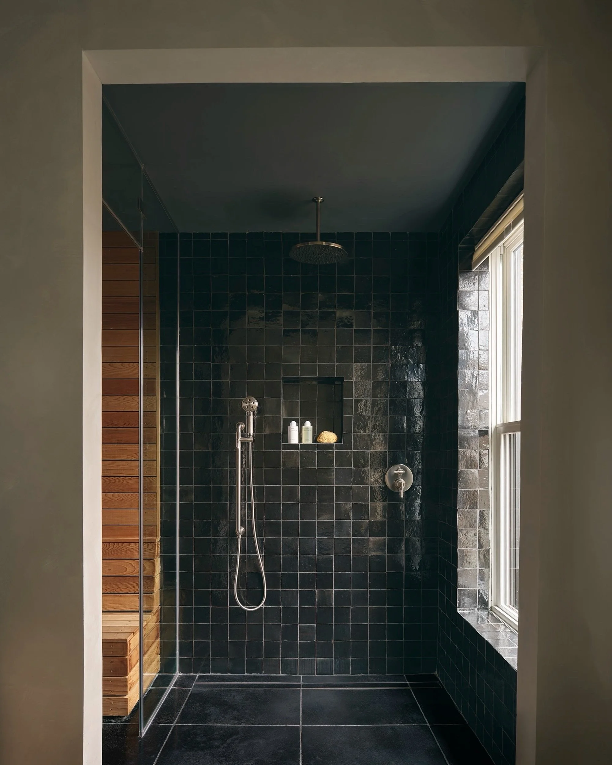A place to slow down at Oculus House.

The spacious shower pairs black zellige wall tile from @cletile with Noir limestone underfoot from @artistic_tile . Just beyond the glass, cedar seating brings warmth to the sauna. Together, the spaces make a da