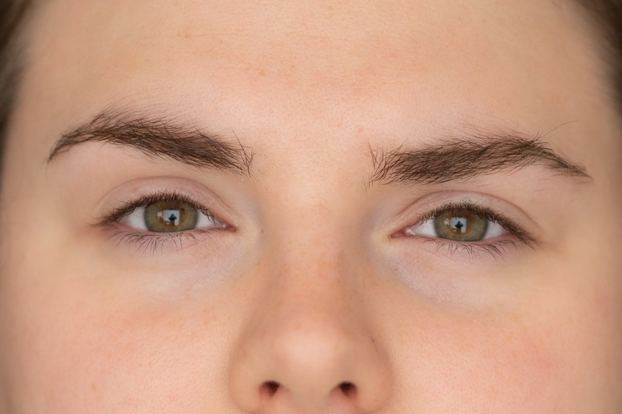 A close-up of a woman's face with thick eyebrows and green eyes. Before and after a Lash Lift and brow lift.