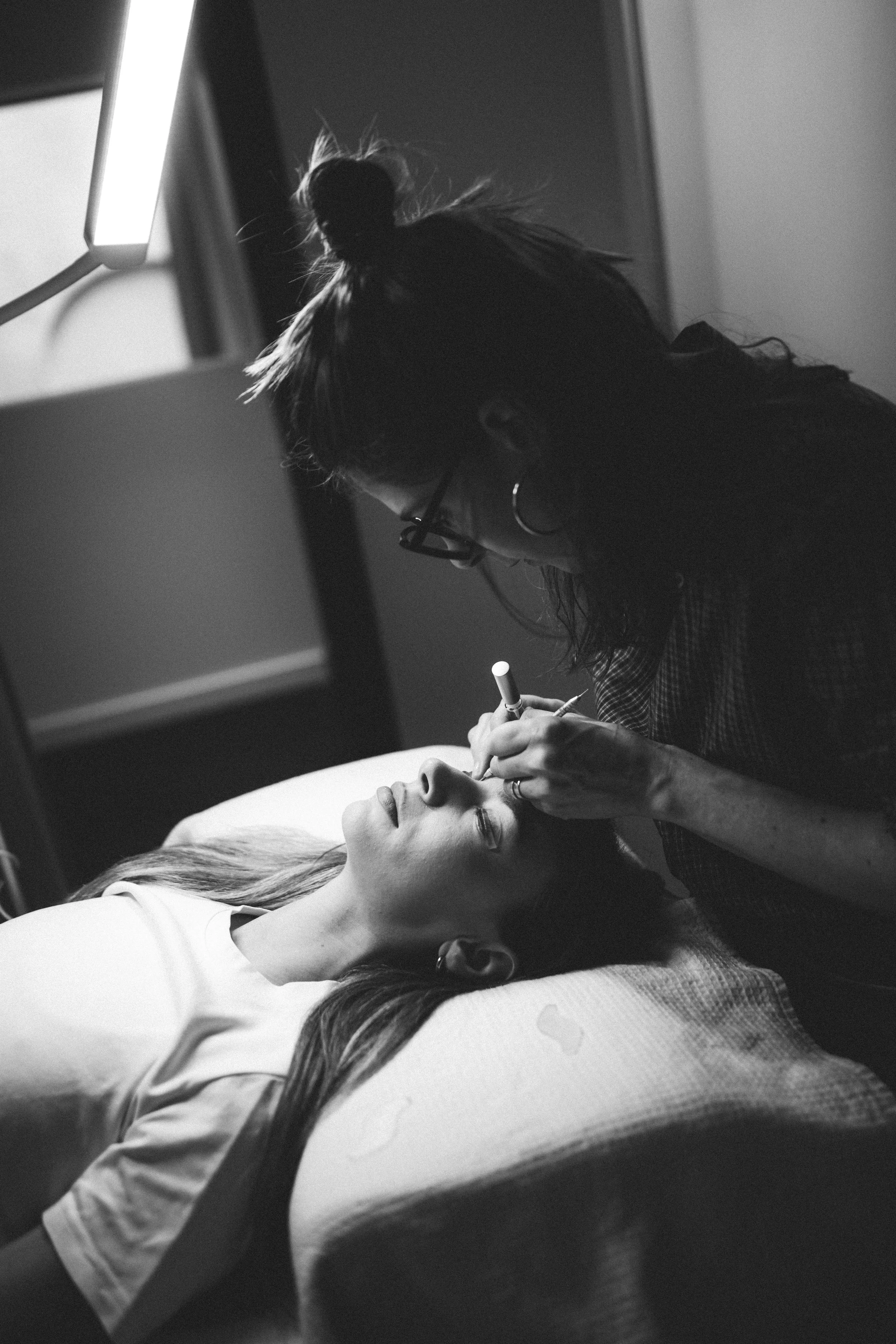 Une femme fait une pose d'extensions de cils,  par une artiste du regard