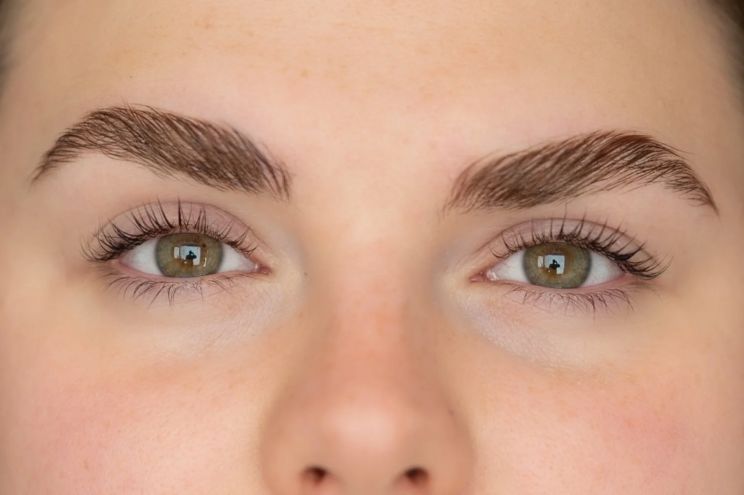 Zoom sur les yeux d'une personne avec des sourcils bien profilés et de longs cils. avant après d'un recourbement de cils et brow lift.