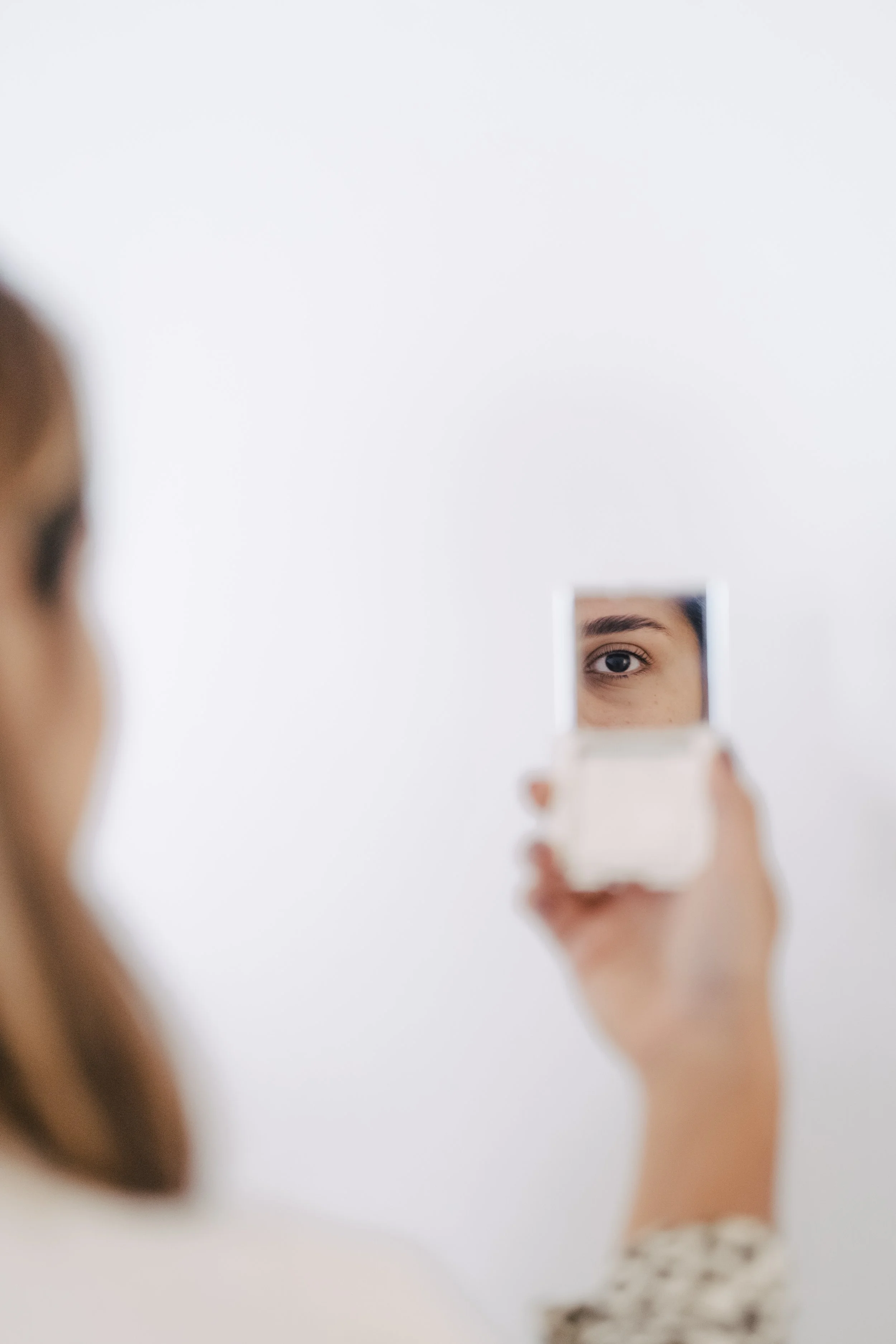 Une personne se regarde dans un petit miroir rectangulaire pour examiner son œil.
