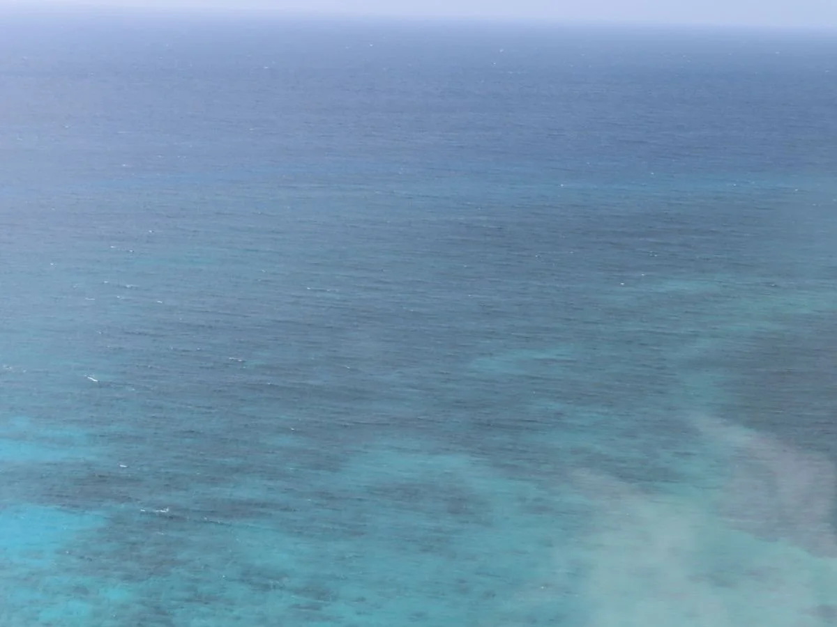 Vue aérienne de l'océan avec des vagues, sous un ciel clair.