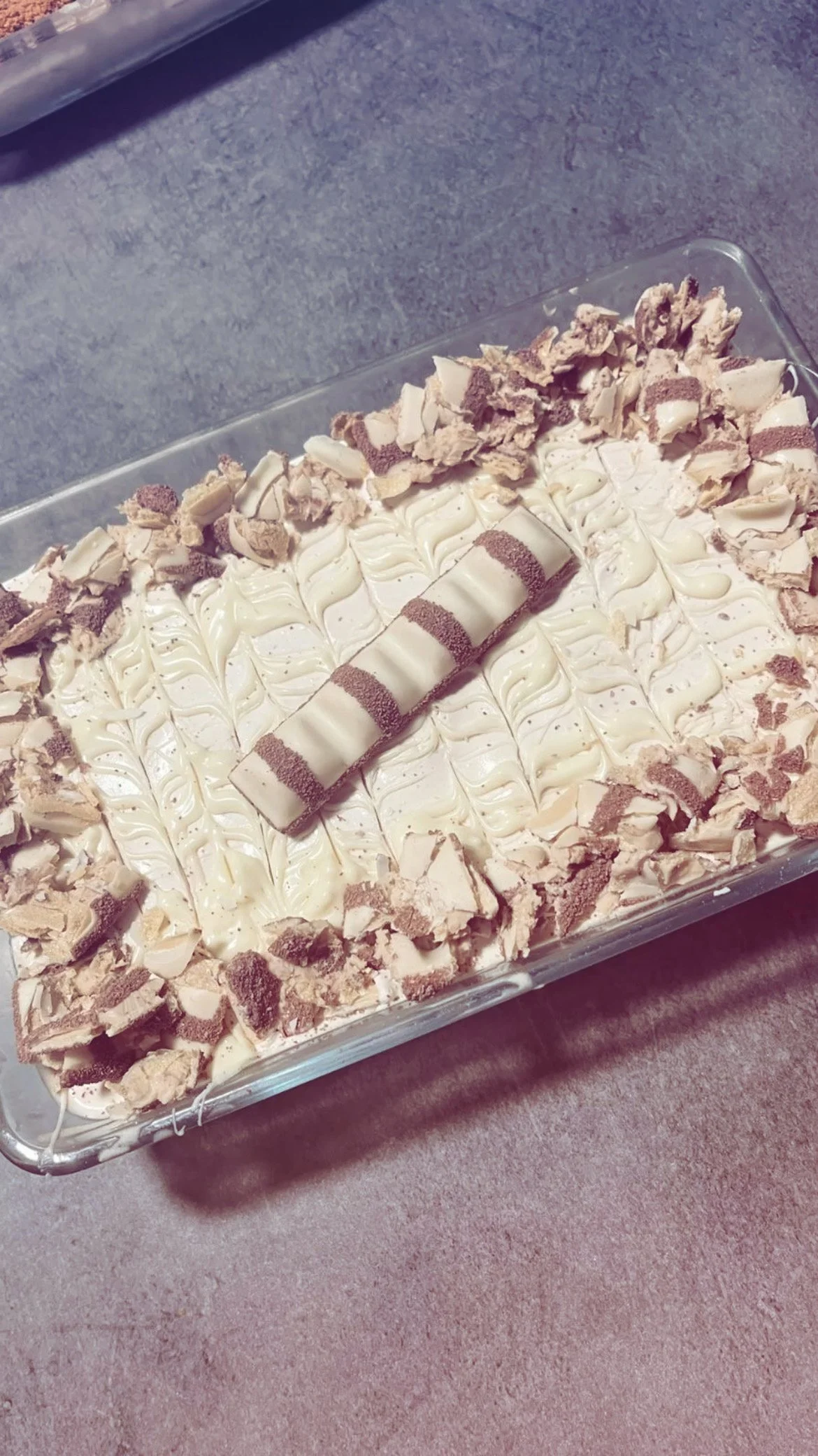 Un plat de dessert, tiramisu, décoré de crème, de morceaux de biscuits ou de meringues, avec un rouleau décoratif sur le dessus.