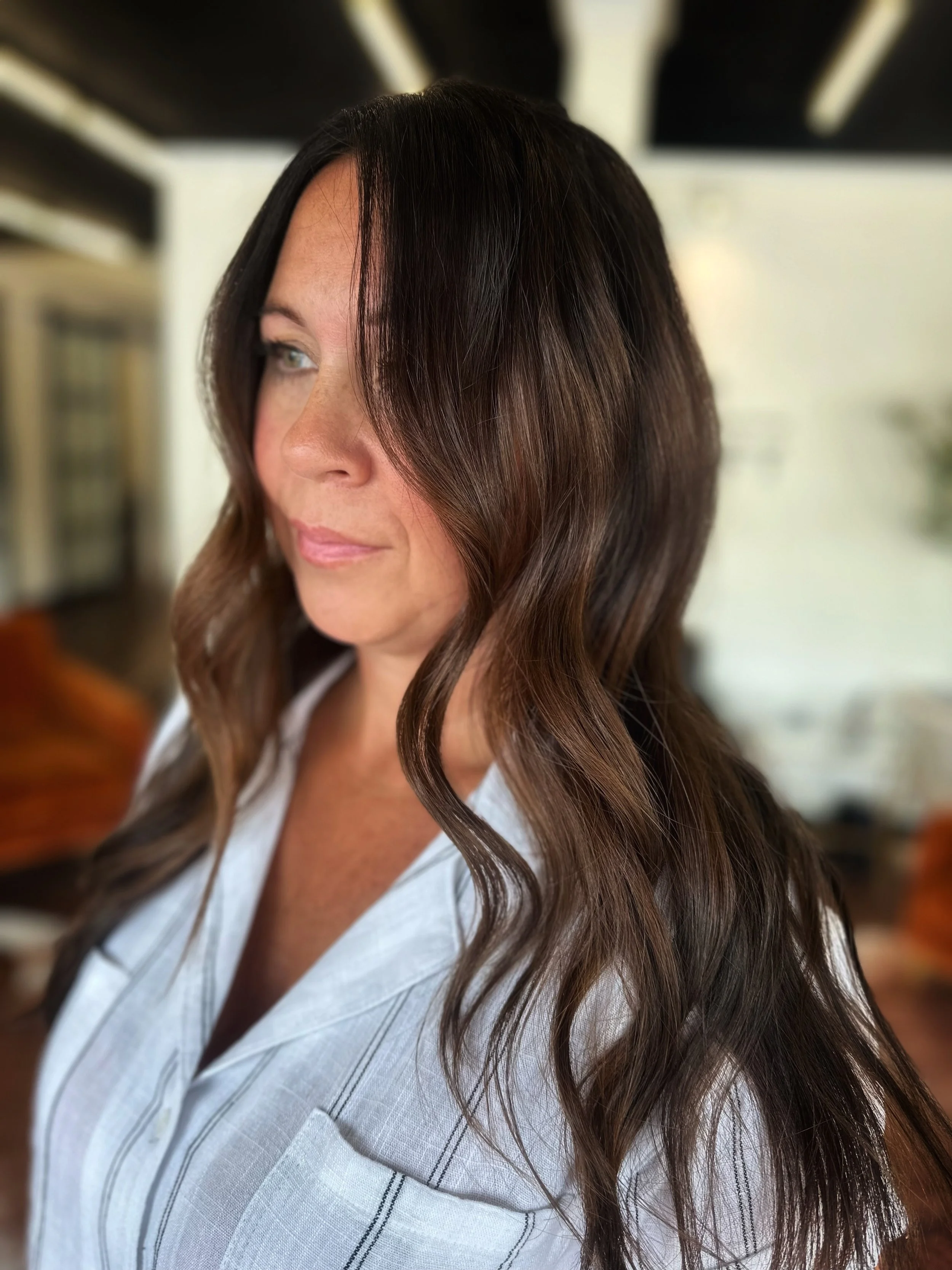 Close-up portrait of a woman with long brown hair wearing a white shirt