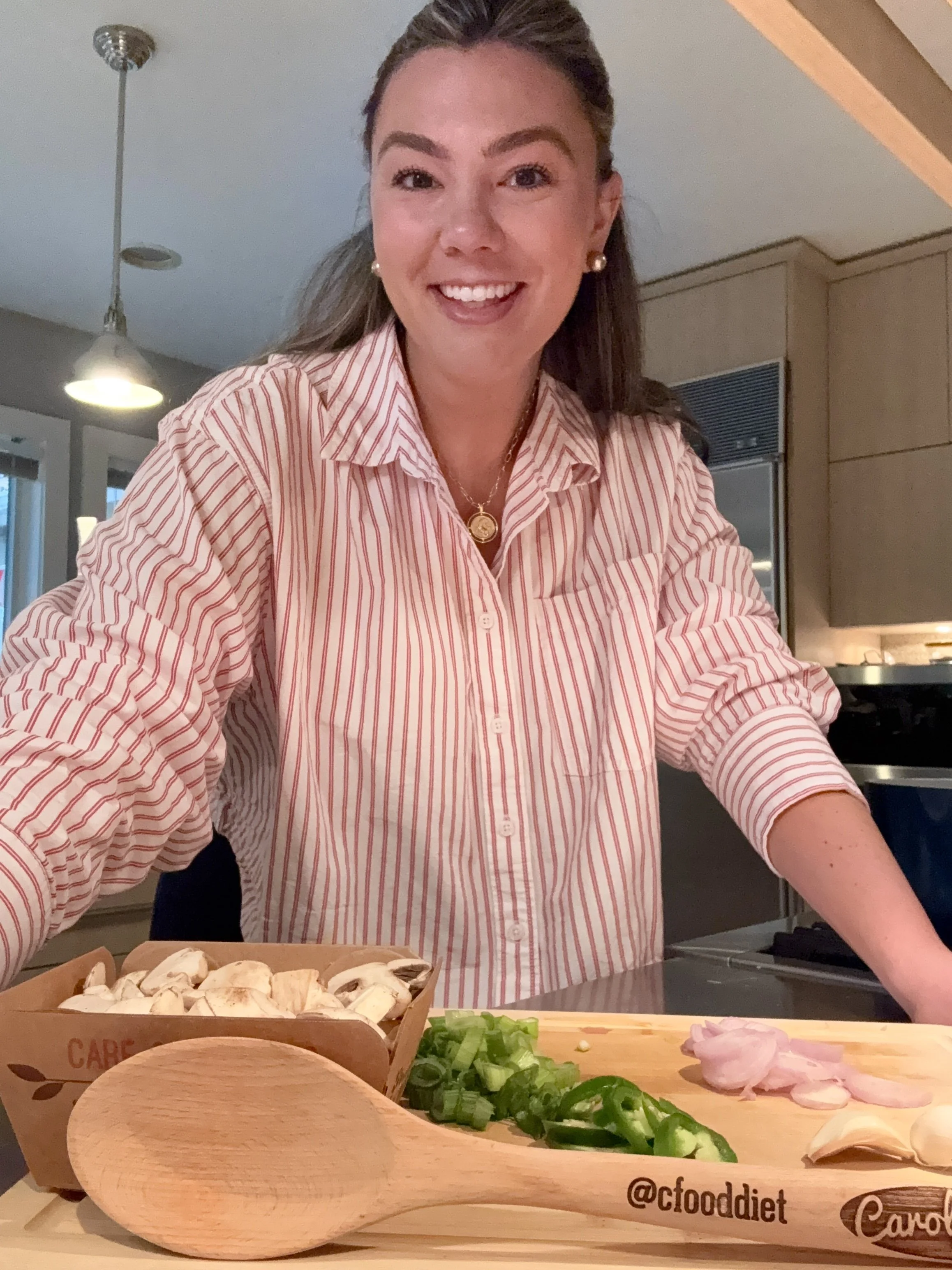 A woman preparing vegetables in a kitchen, smiling at the camera.