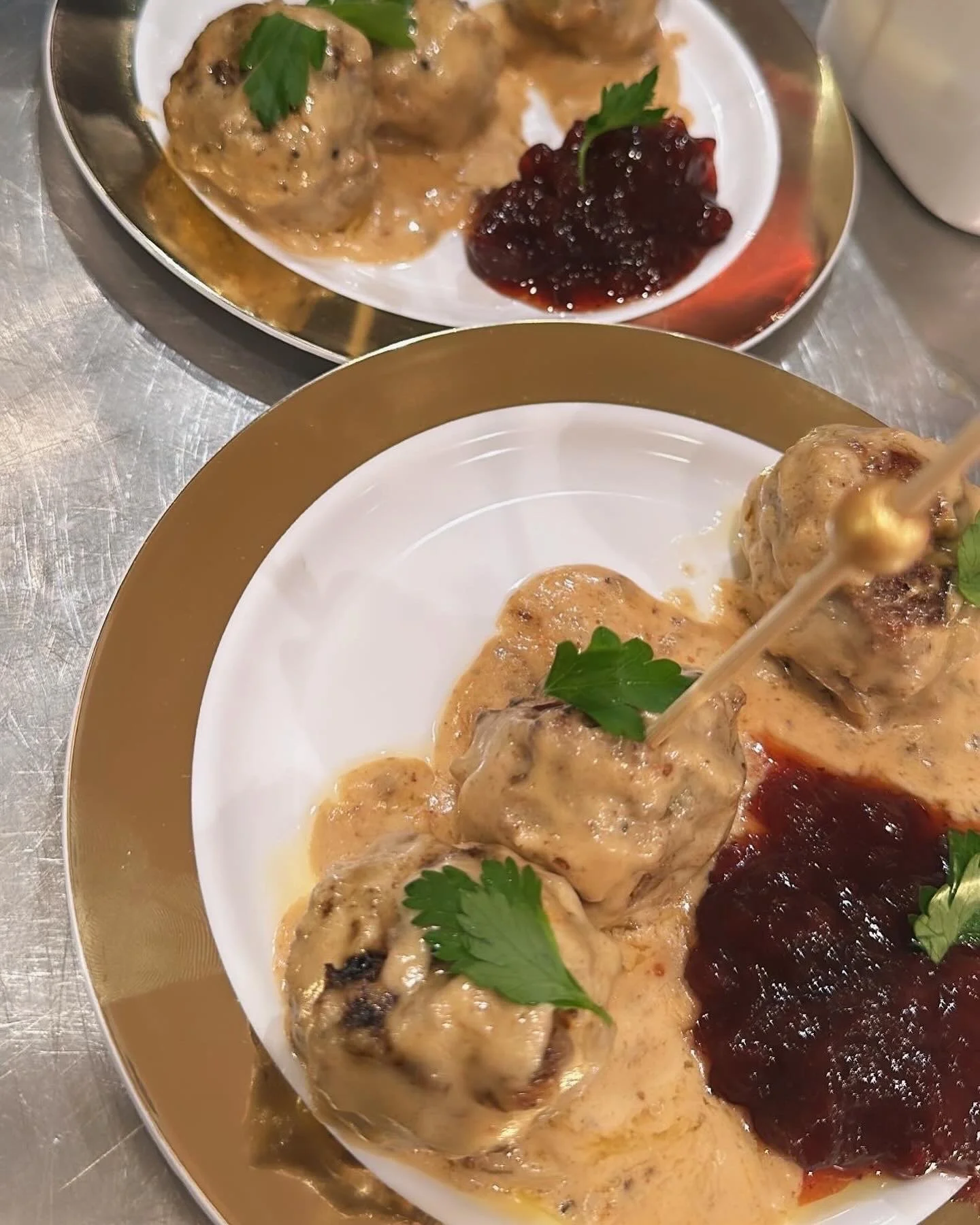 Plate of four Turkey meatballs with gravy, garnished with parsley, served with cranberry sauce.