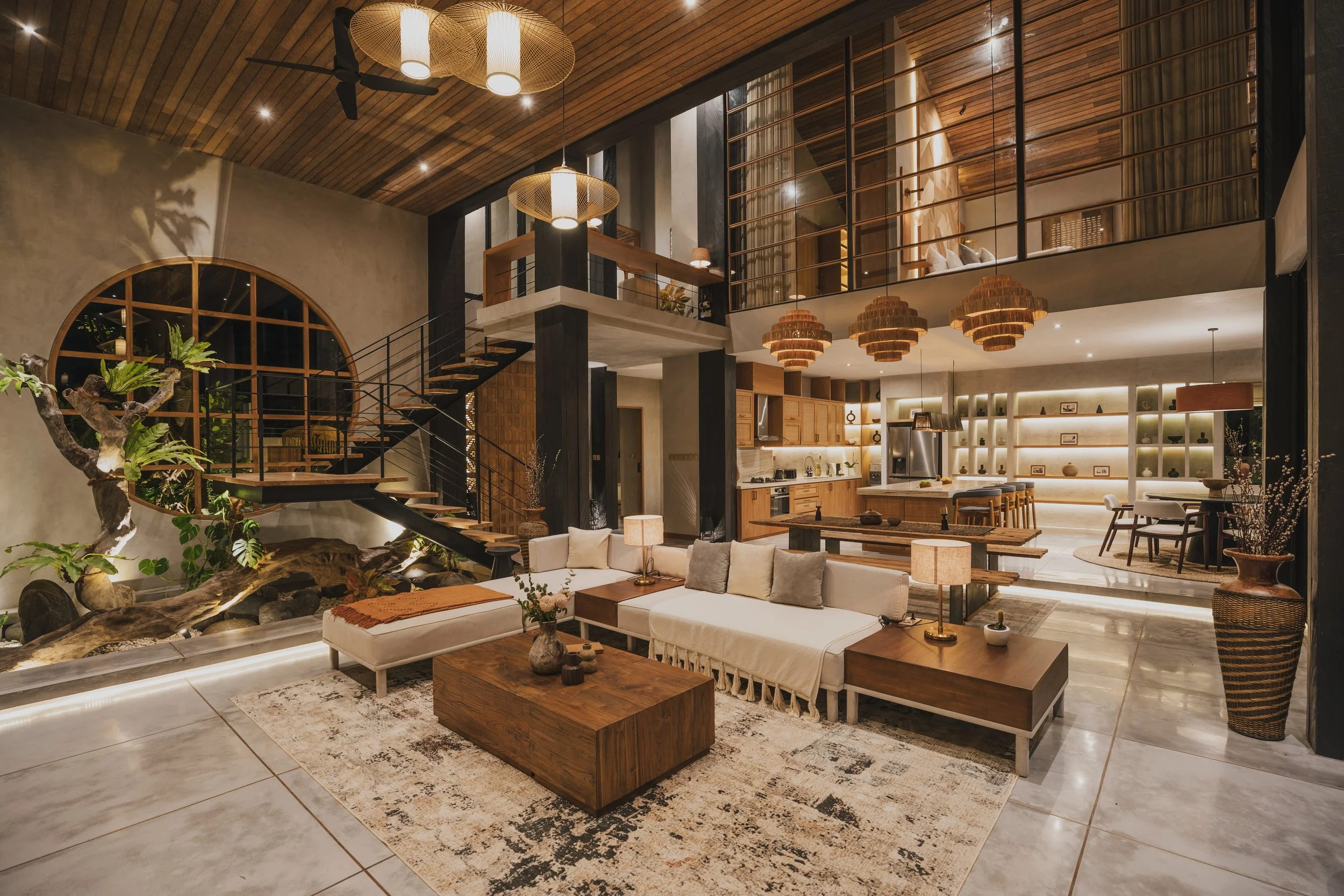 Luxury open-concept living room, kitchen, and dining area with modern and rustic decor, wooden accents, and large windows.