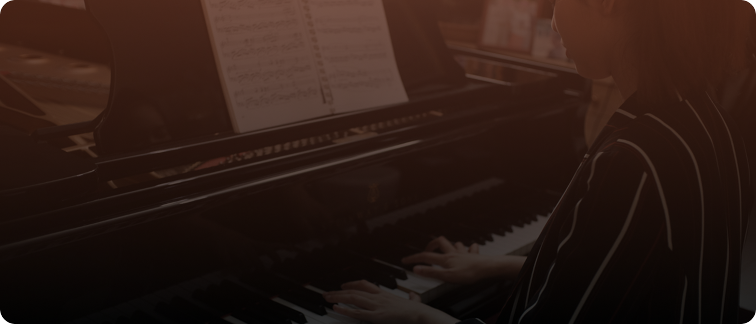 A person playing a grand piano, reading sheet music placed on the music stand.
