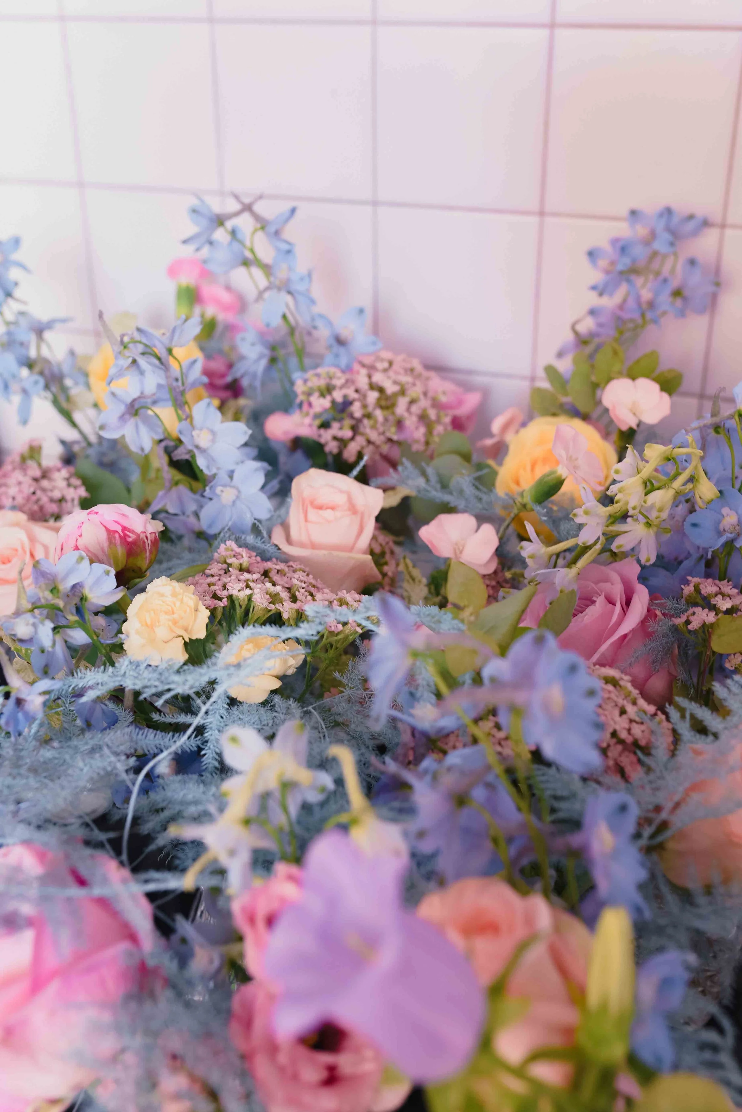 Bouquet de fleurs avec des roses roses, des fleurs bleues, et d'autres petites fleurs dans un décor naturel.