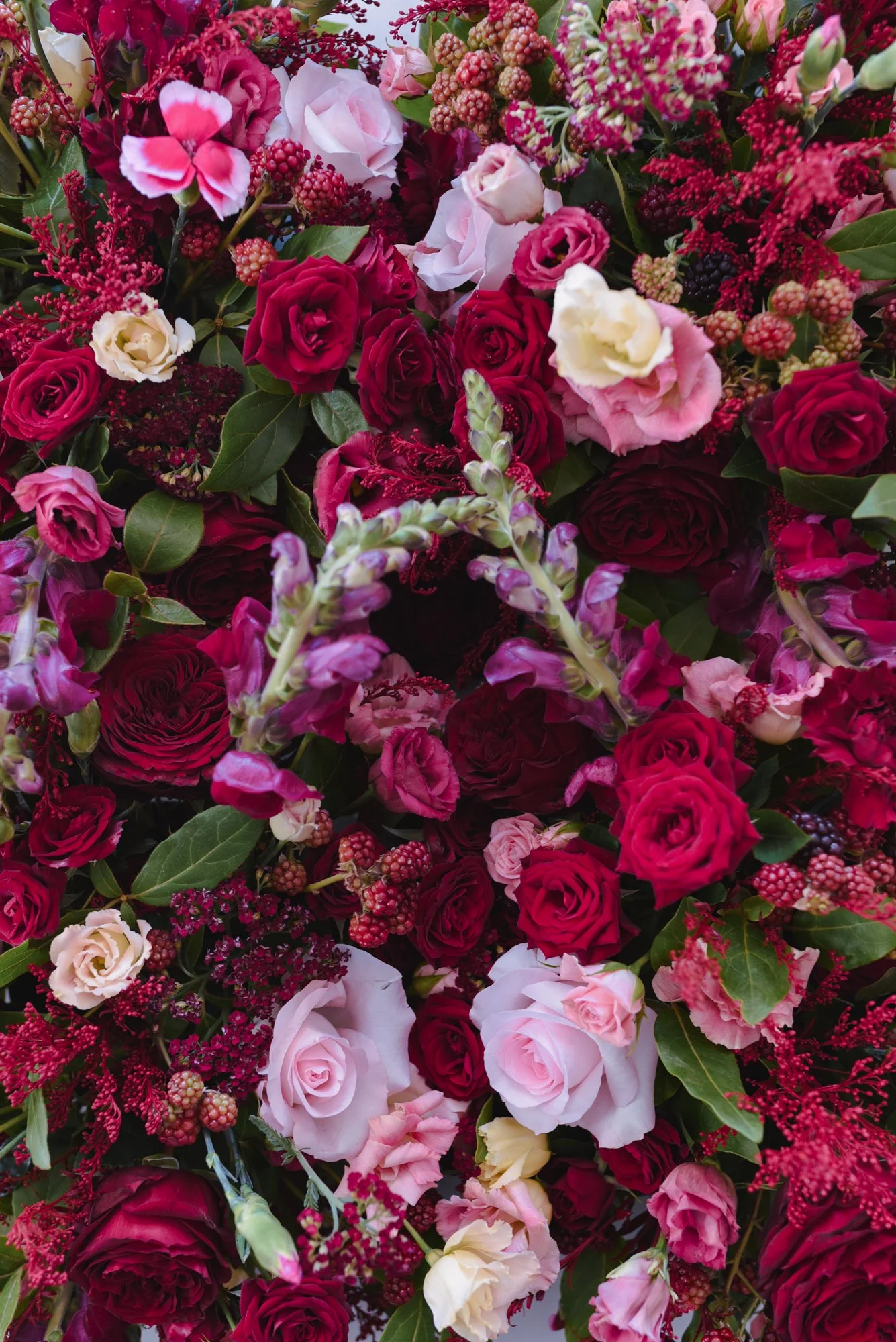 Un bouquet composé de roses rouges, roses roses, fleurs rouges et feuillage vert