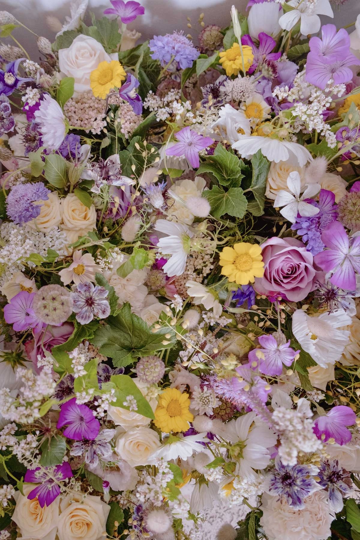 Un assortiment de fleurs colorées, notamment des roses, des marguerites, des fleurs violettes et blanches, et diverses autres fleurs dans des tons pastel, formant un bouquet dense et riche.