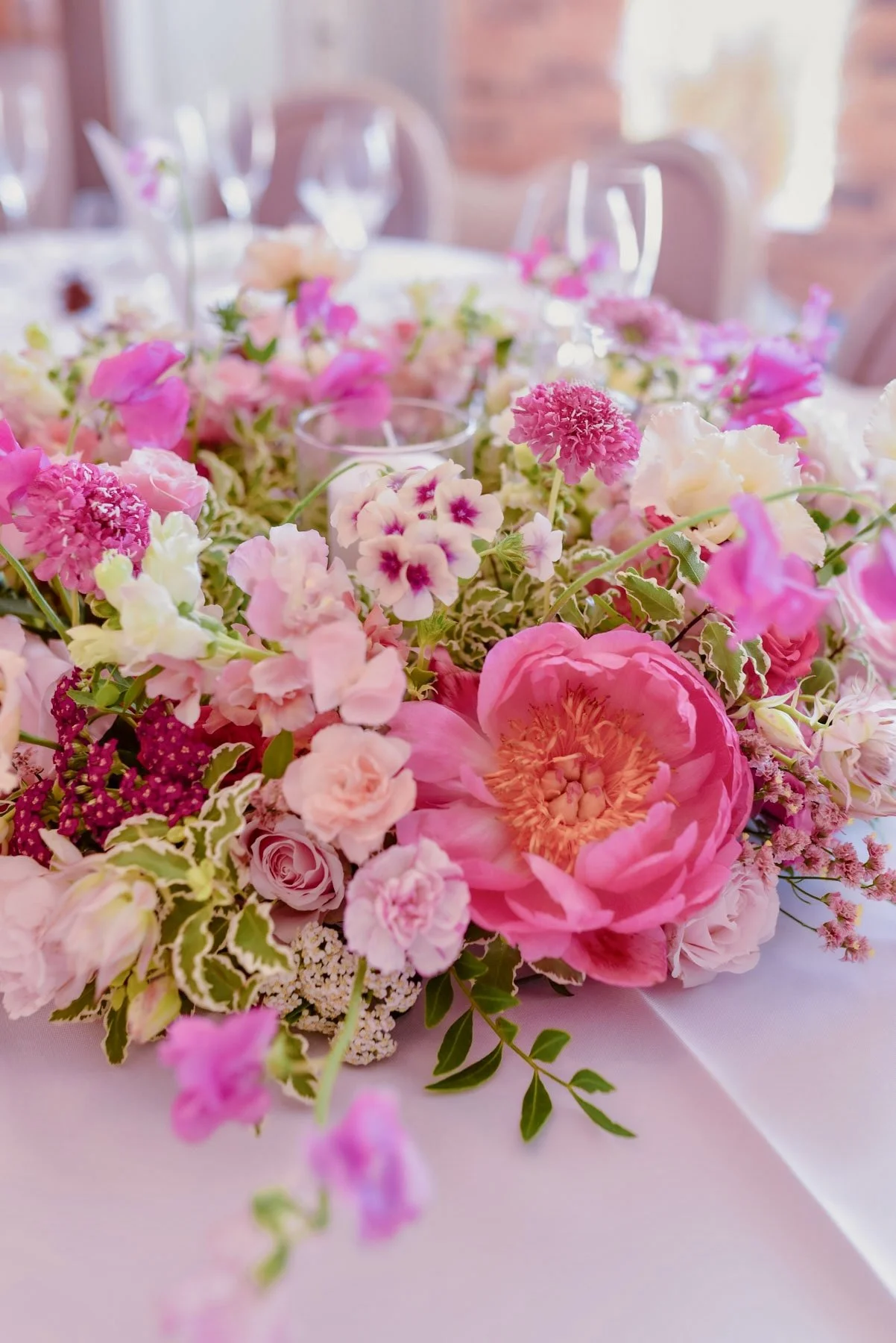 Un centre de table avec un arrangement floral composé de fleurs roses, blanches et violettes, servant probablement pour une réception ou un événement spécial.