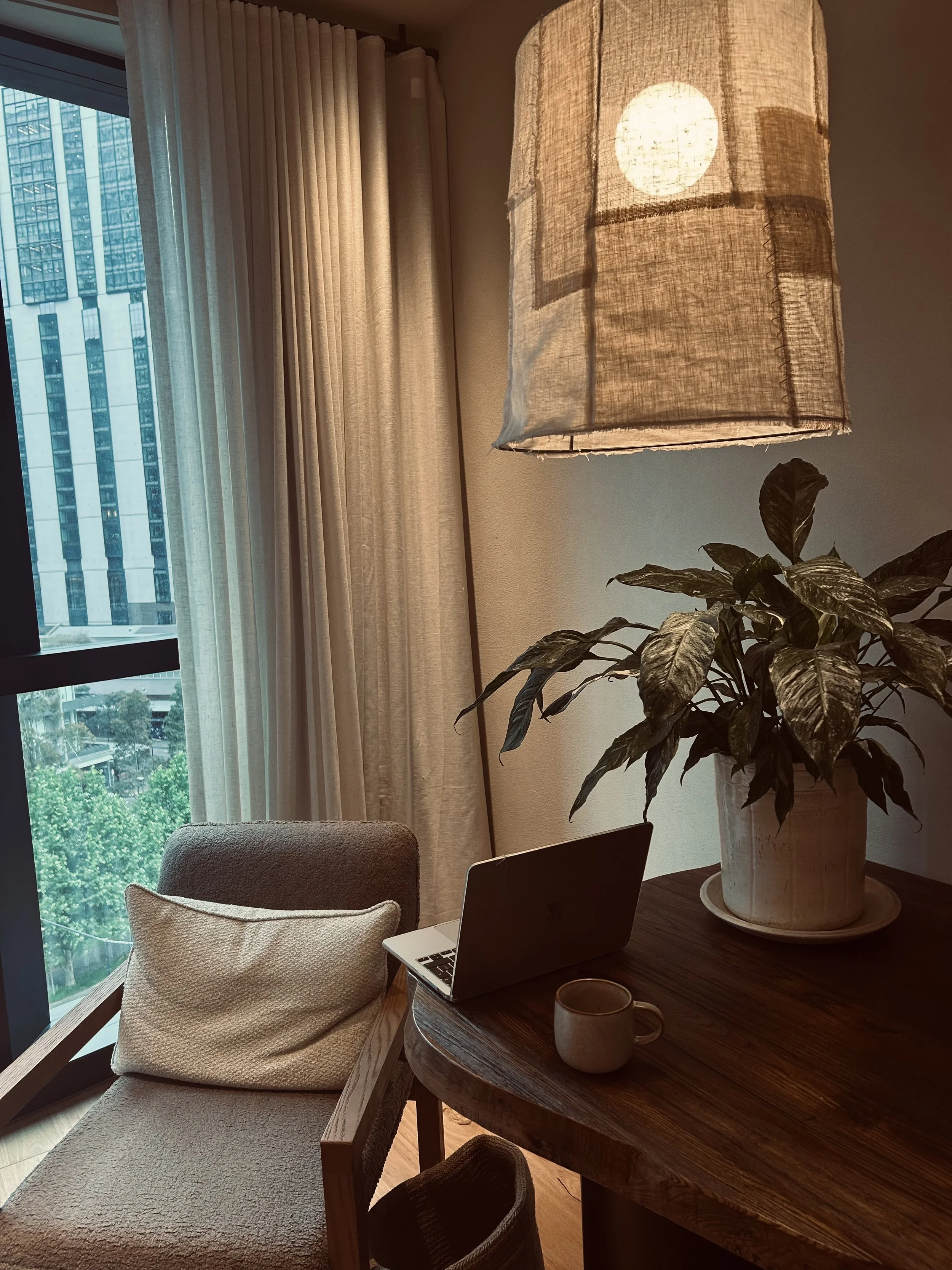 Person typing on a laptop at an outdoor wooden table, with a notebook and pen nearby.