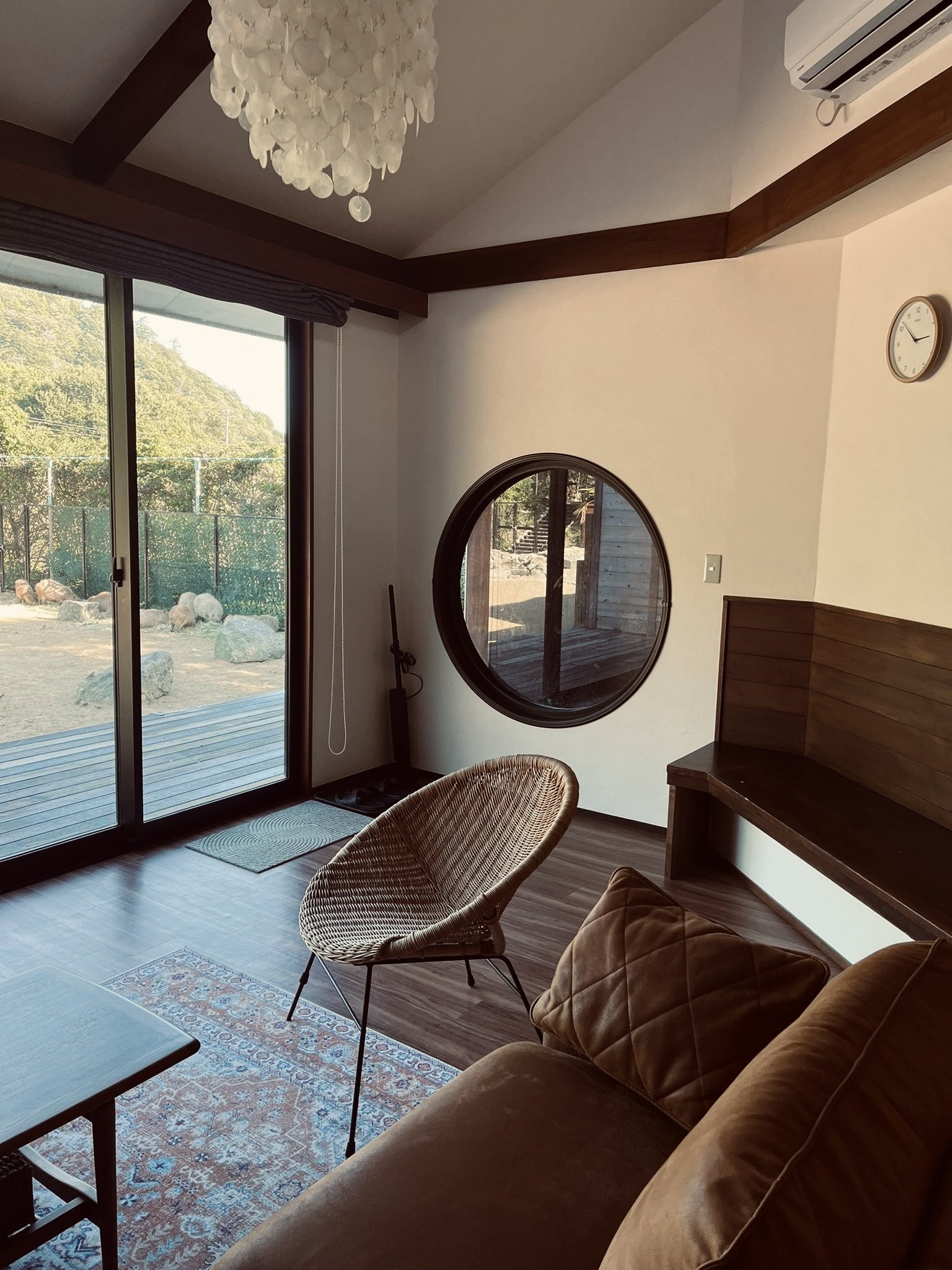 Bohemian-style interior with woven pendant light, rattan furniture, and textured pillows against a stone wall mural.