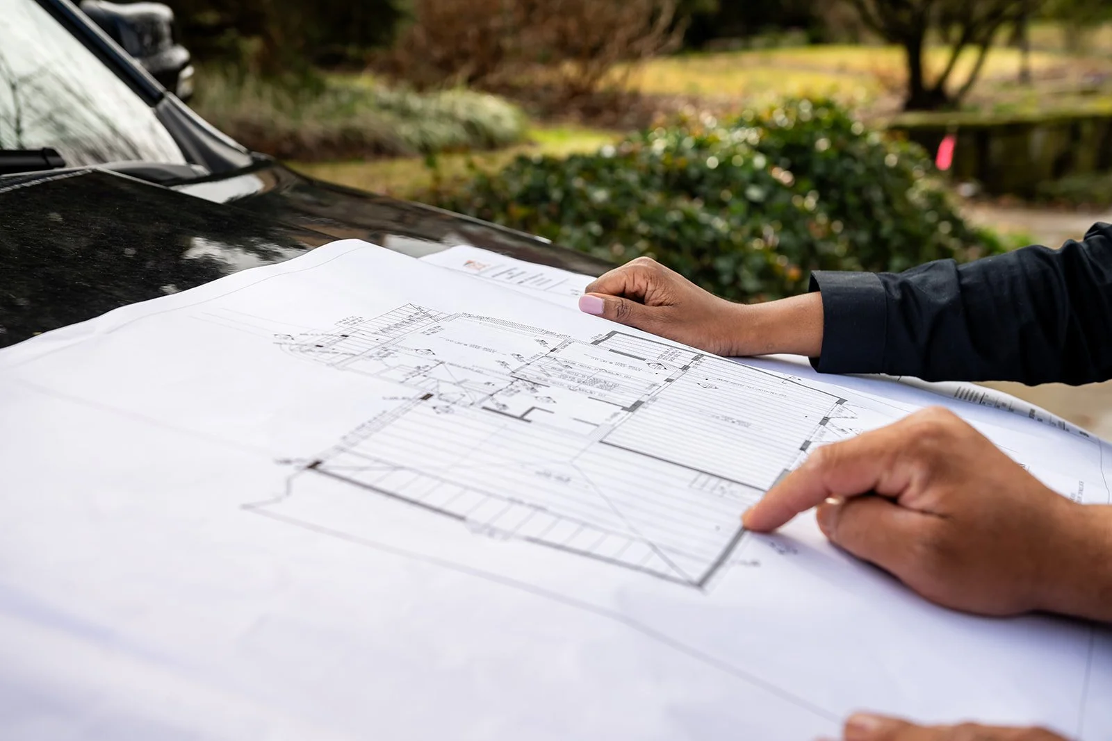 Ngage properties Group team reviewing architectural blueprints at home construction site.