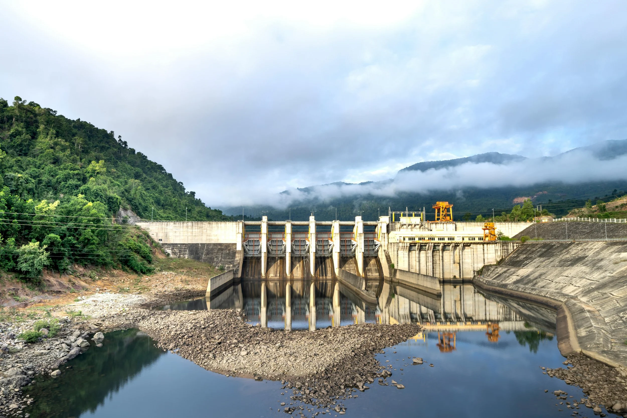 A hydroelectric dam built in a green, mountainous valley..