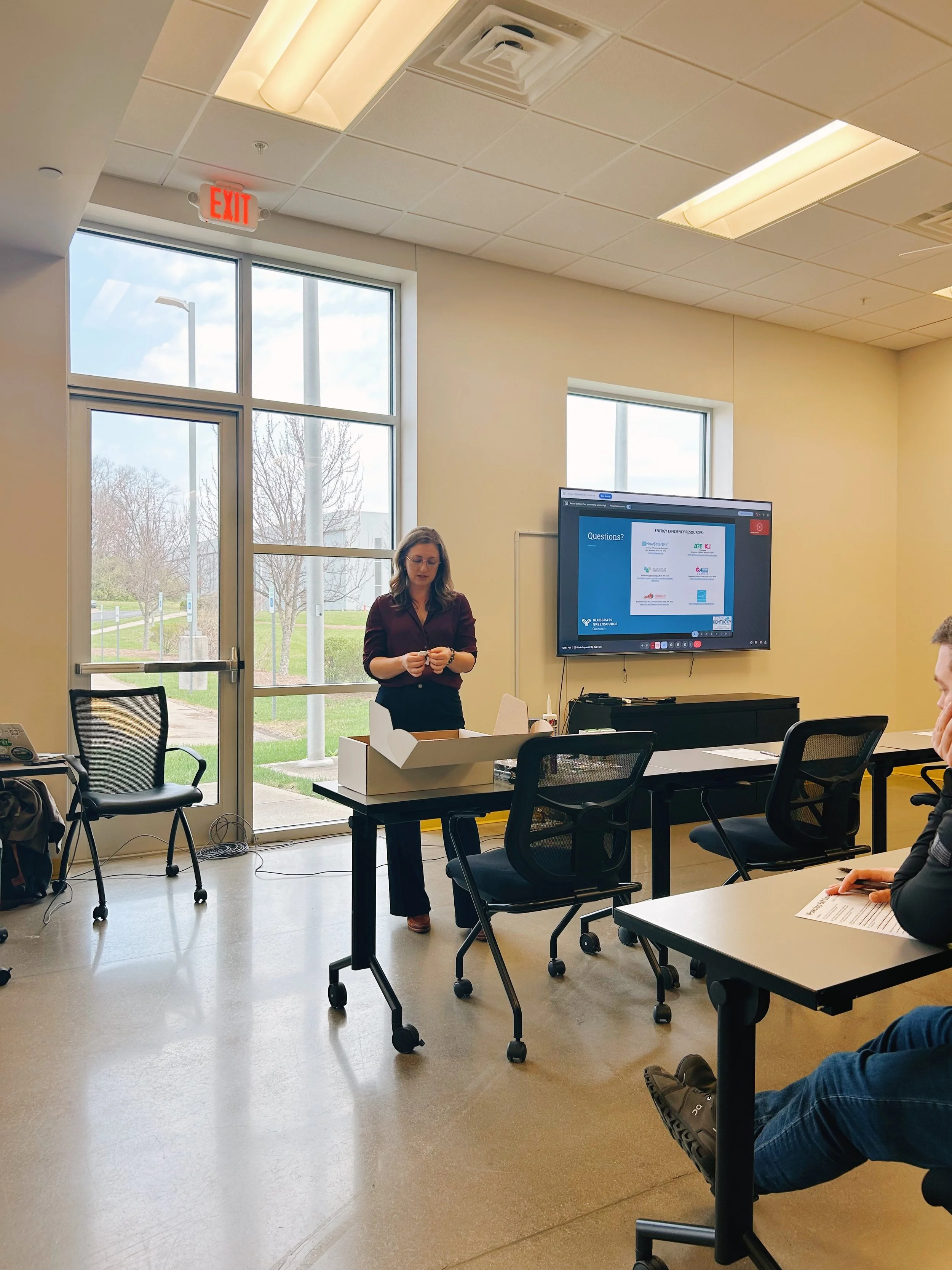 Woman stands at the front of the room and gives a presentation.