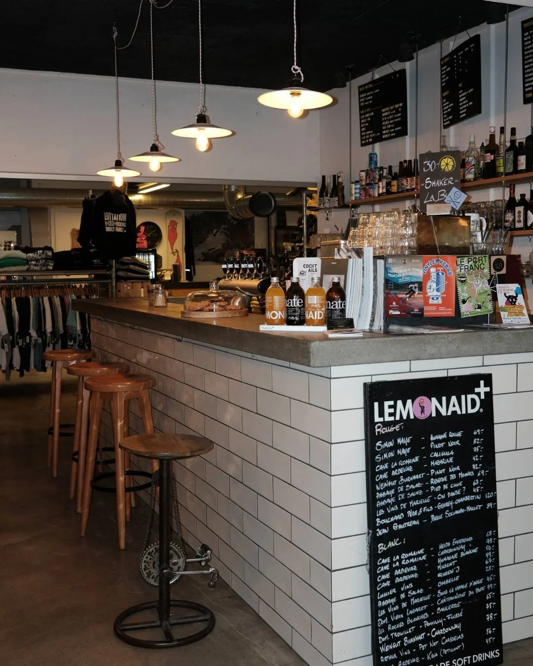 Un comptoir de bar avec menu, produits et éclairage suspendu dans un café ou un bar moderne.