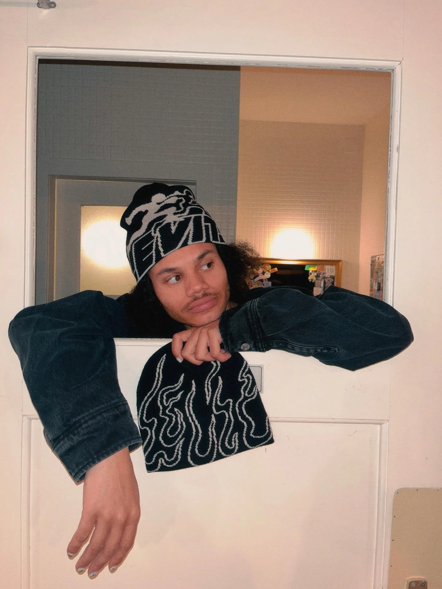 Une personne regarde au travers d'une fenêtre ou ouverture dans une porte, avec un décor intérieur en arrière-plan.