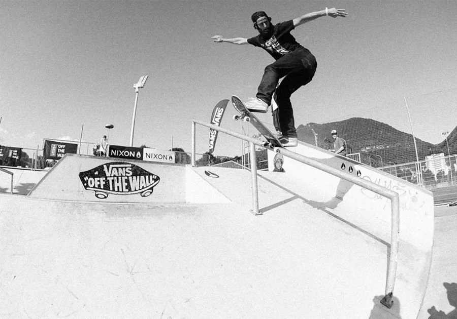 Skateur en train de faire une descente en skateboard sur une rampe de skatepark, en noir et blanc.