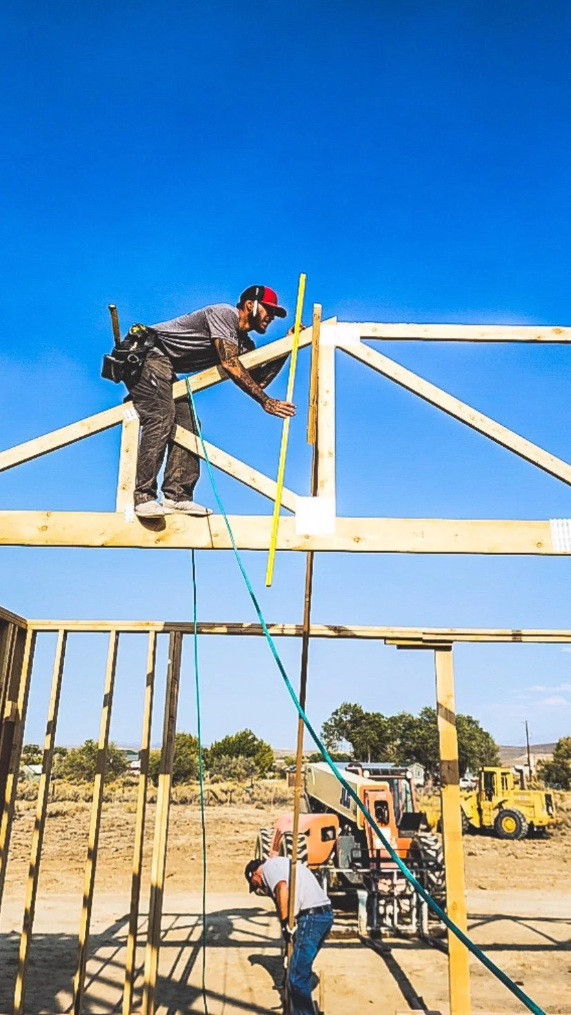 A construction worker installing wooden beams for the framing of a new and custom designed home.