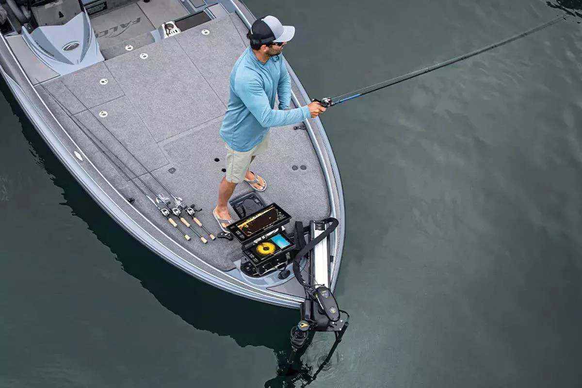 A man fishing from a boat in the water, with fishing rods, tackle box, and boat motor visible.