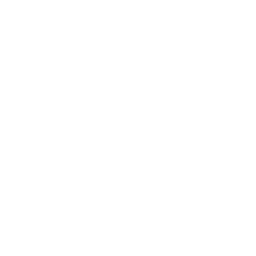 Silhouette of a person sitting on a bench, reading a book, with greenery and trees in the background.