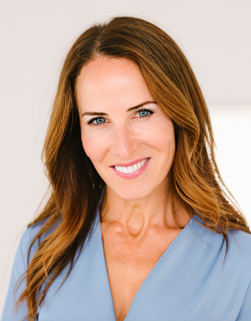 Close-up of Dr. Sarah de la Torre, a woman with brown hair and blue eyes smiling, wearing a light blue scrub top.
