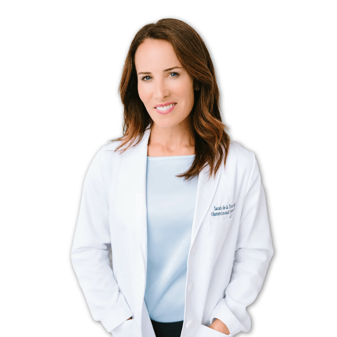 Dr. Sarah de la Torre, a woman with shoulder-length brown hair wearing a white lab coat and a light blue top, smiling at the camera.