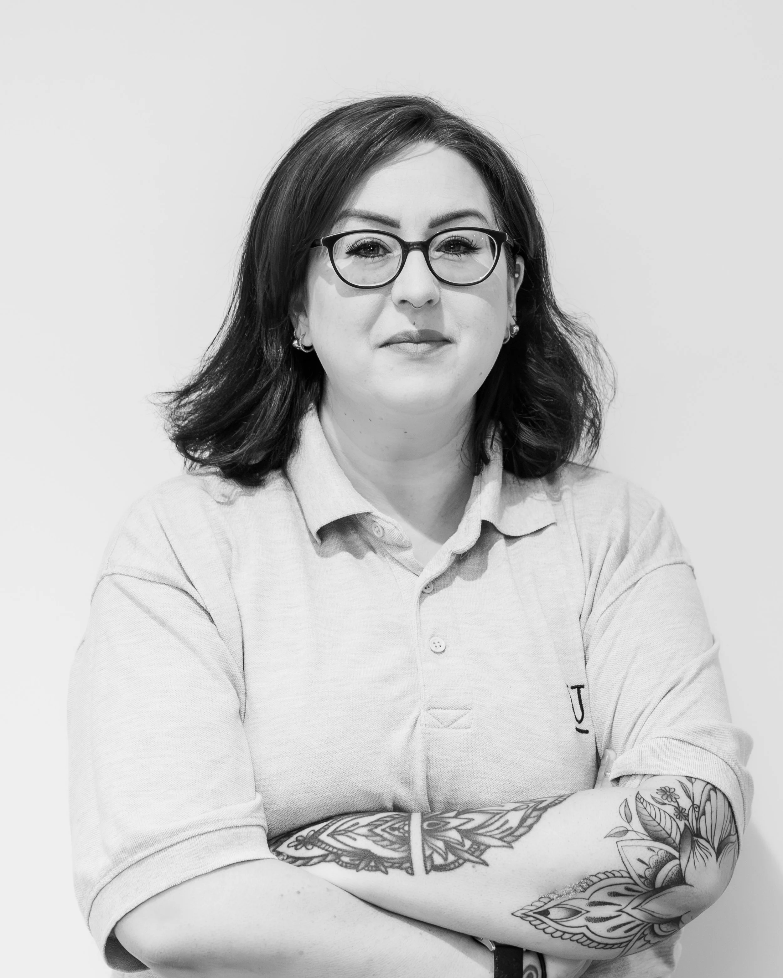 A woman with brown hair and glasses smiling outdoors, leaning against a white van door