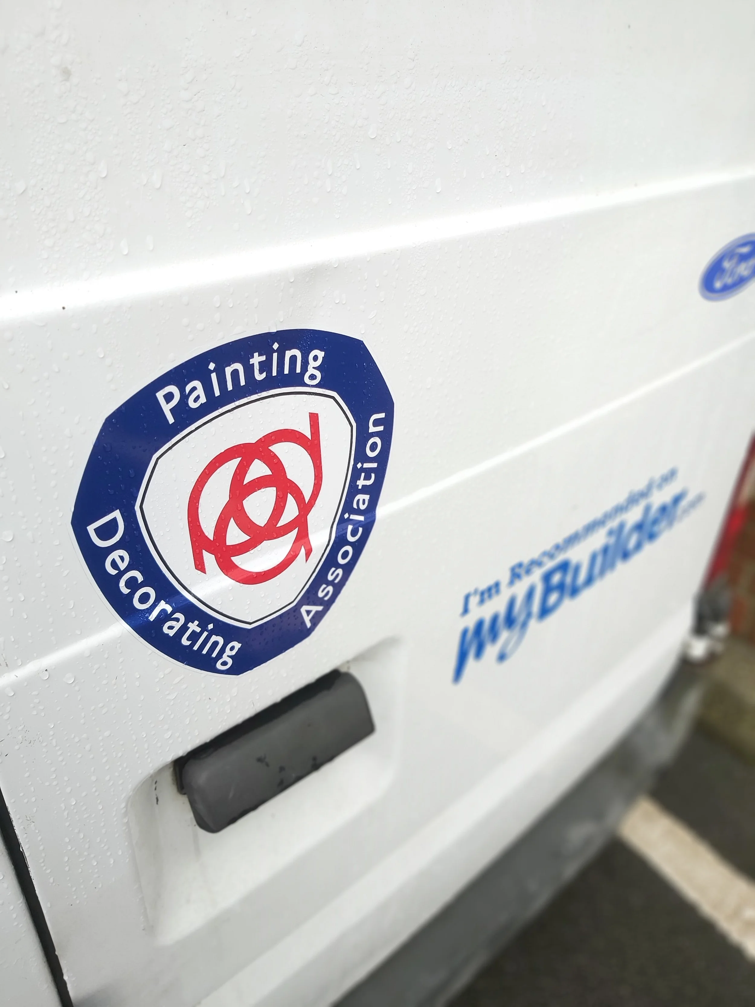 Close-up of a white vehicle door with a sticker that reads 'Painting Declaration' and a logo that includes red and blue colors.
