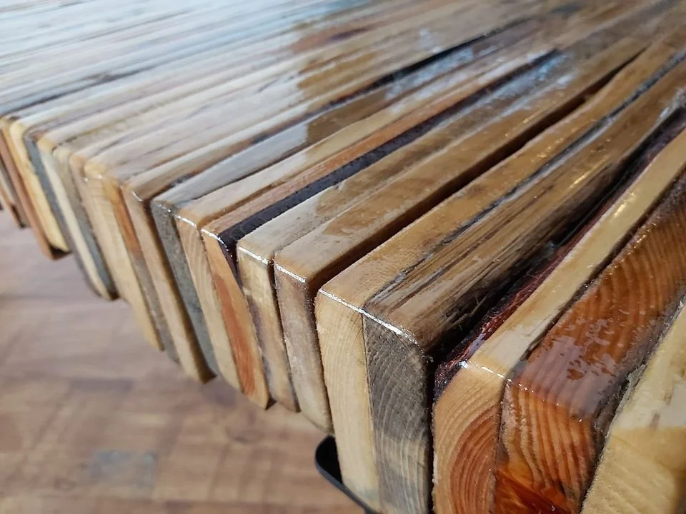 A wooden table with a glossy finish showing various shades of wood grain.