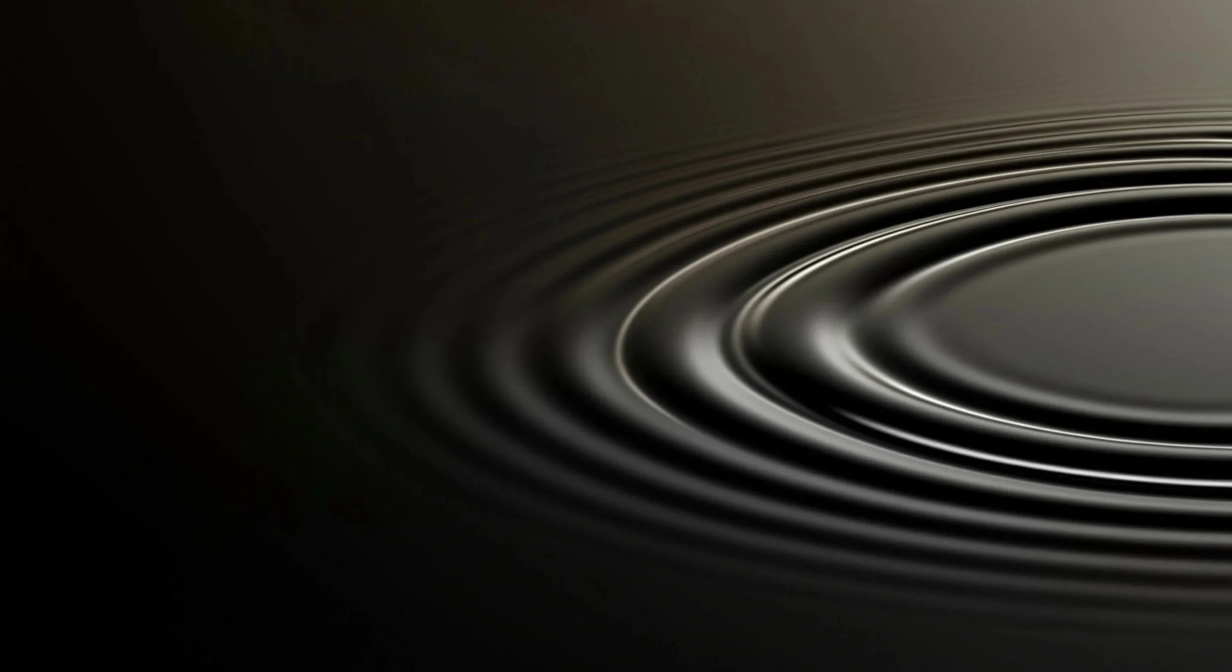 Close-up of a speaker cone with concentric rings in a dark setting.