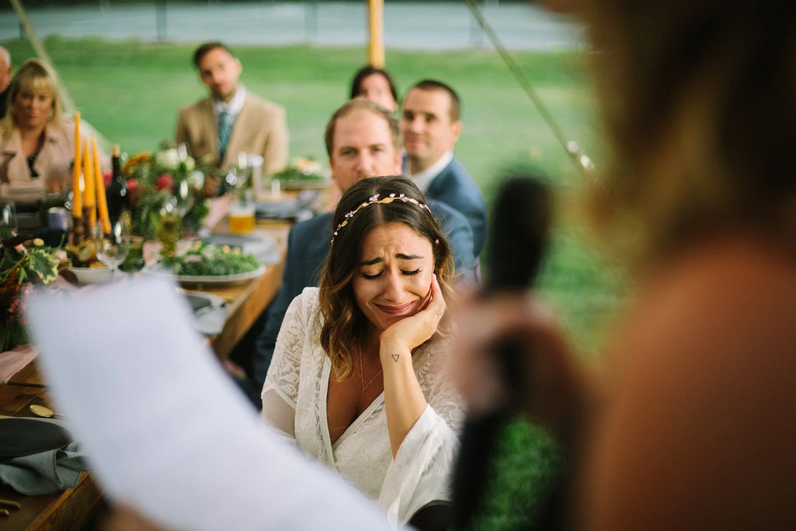 A woman appears emotional and upset during her wedding reception, sitting at a table with guests in the background.