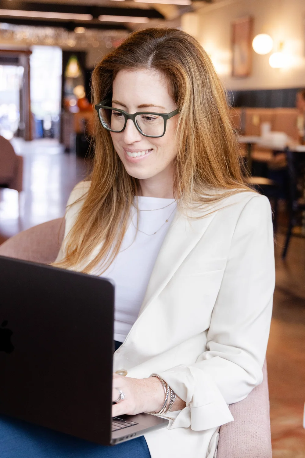 Jessica Rousseau, board-certified Family Nurse Practitioner, smiling while working on a laptop