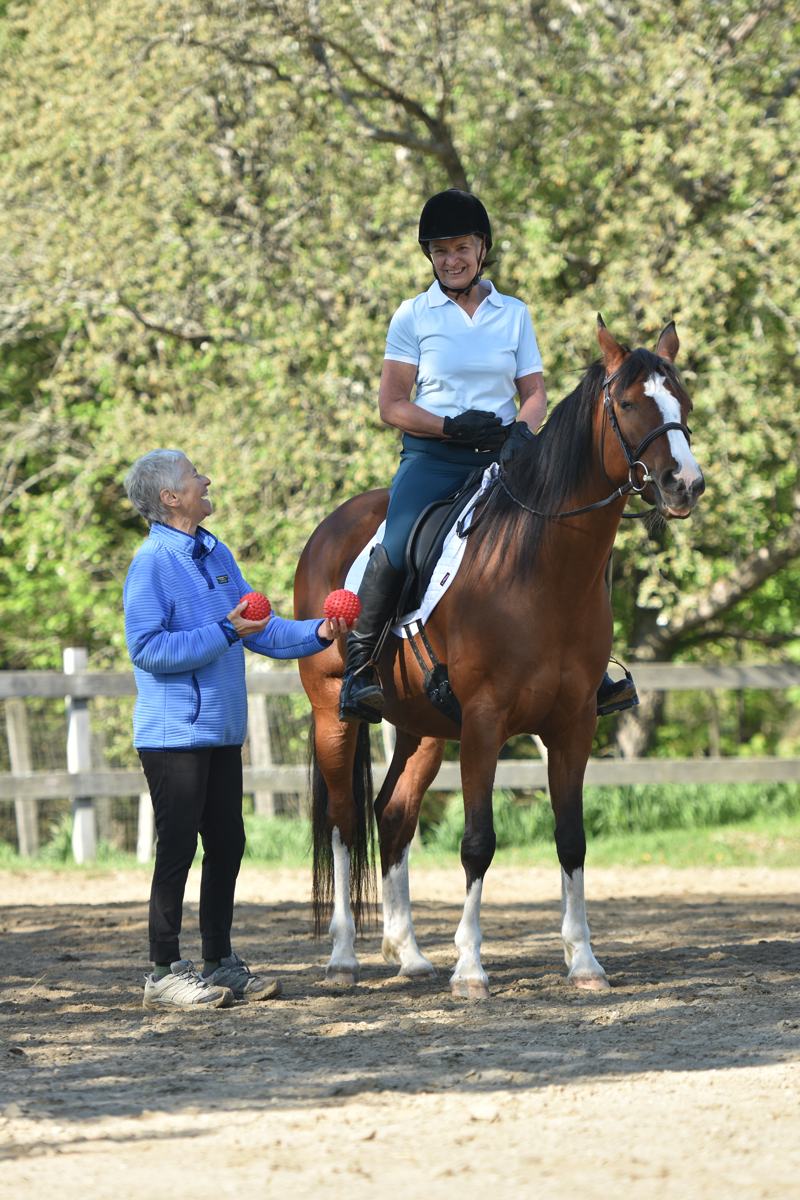 Teacher Joyce Kramer teaching horseback rider about her core strength in saddle.
