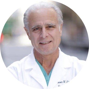 Portrait of an older male doctor with white hair wearing a white lab coat, standing outdoors.