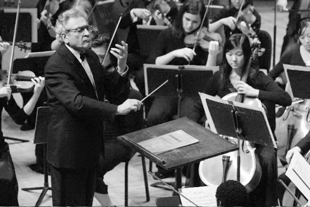 Orchestra conductor leading musicians during a performance.