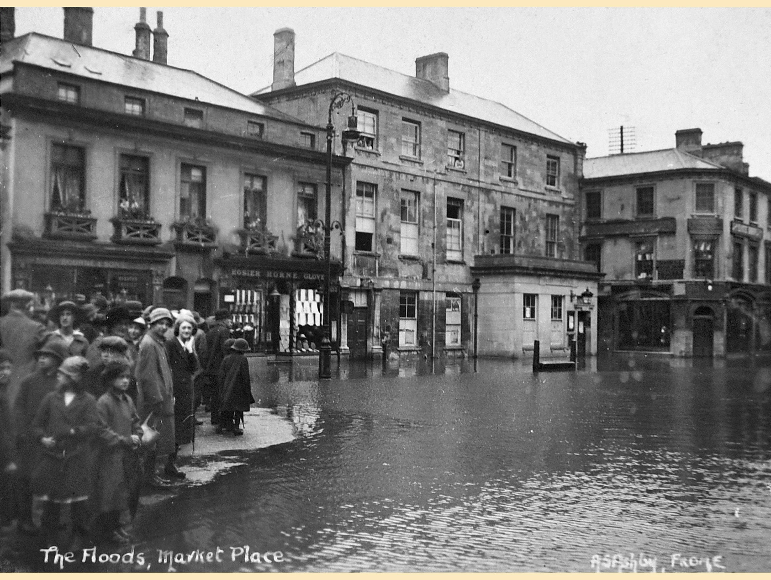  FROME MARKET PLACE FLOODING -  
This 1920's photo shows how far the River Frome often reached in the Market Place before the extensive work completed by the River Authority in the 1970s stopped the flooding altogether in the Town centre.
